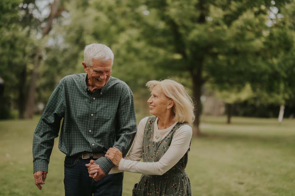 Grandparents walking arm in arm through the park, laughing together