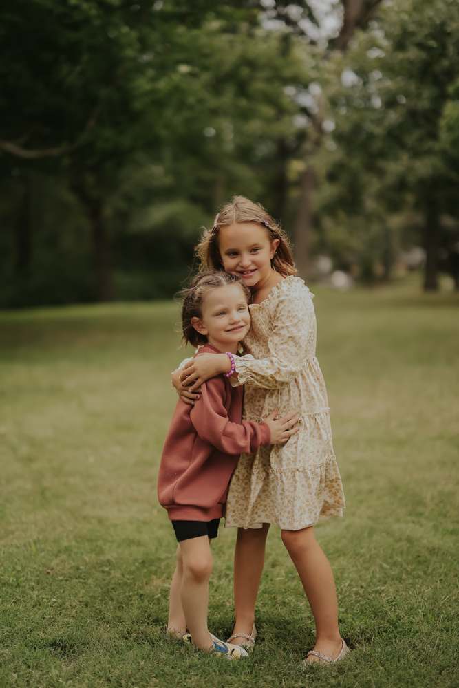 Sisters holding on to each other in the grass