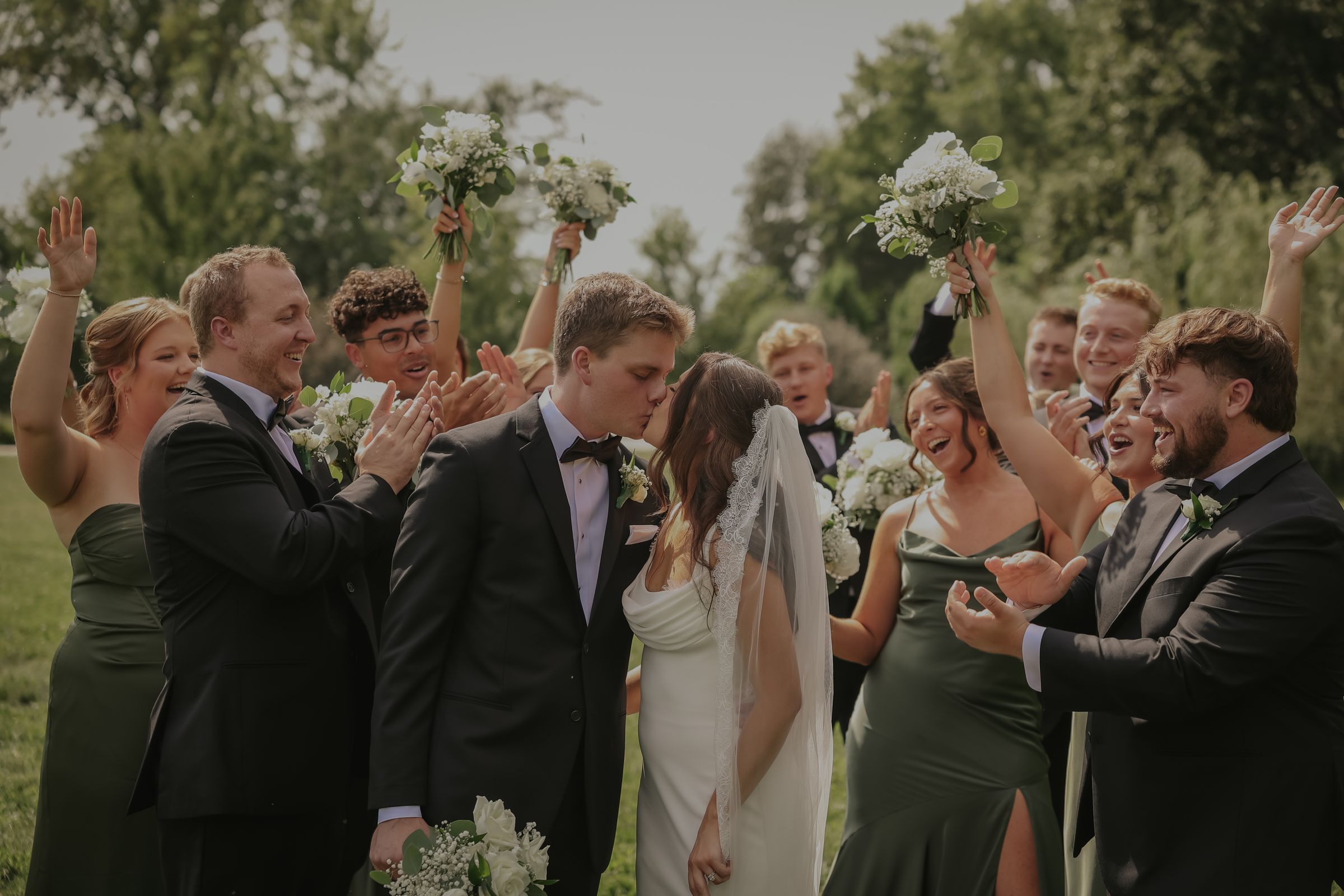 The wedding party cheering as the couple kiss