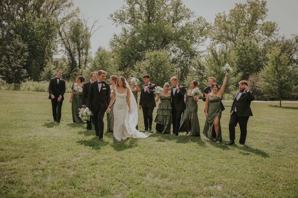 The full wedding party walking out across the field